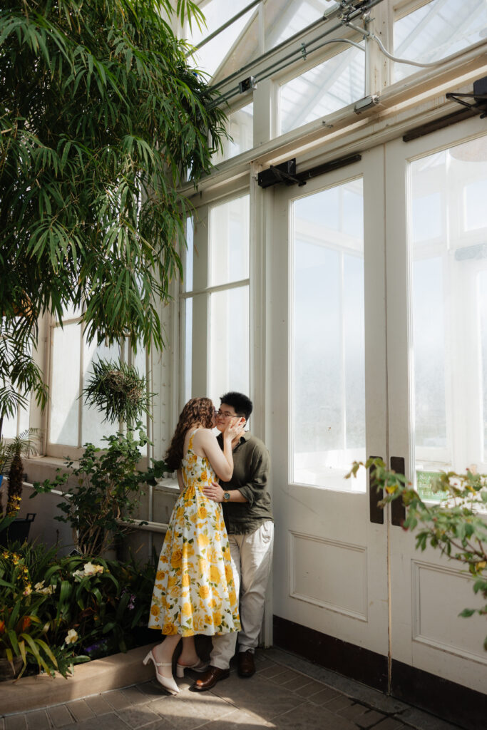 Romantic spring engagement photos in a botanical garden greenhouse with lush greenery and flowers