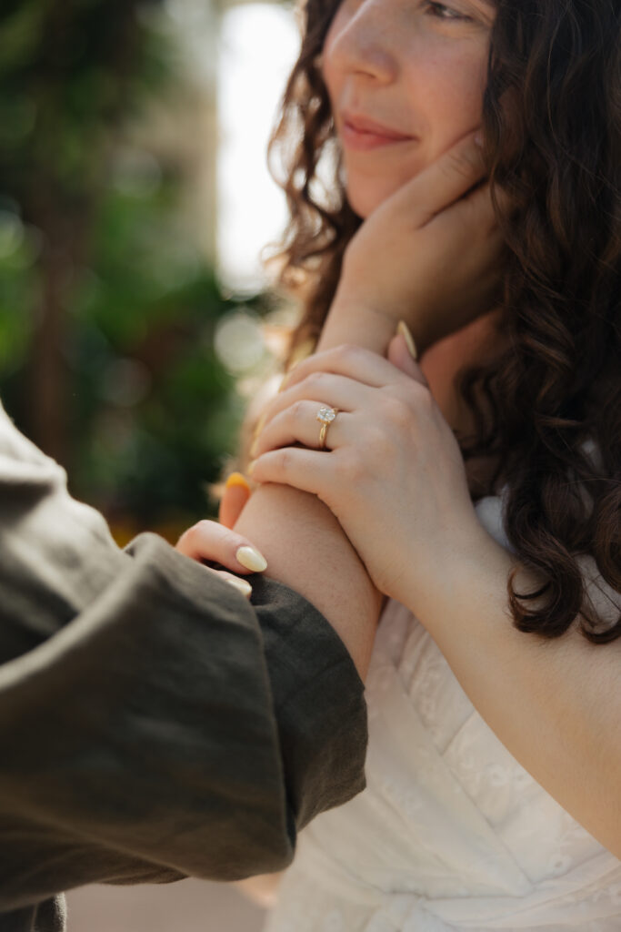 Close up of engagement ring on bride's hand with floral dress details during Buffalo Botanical Gardens engagement session
