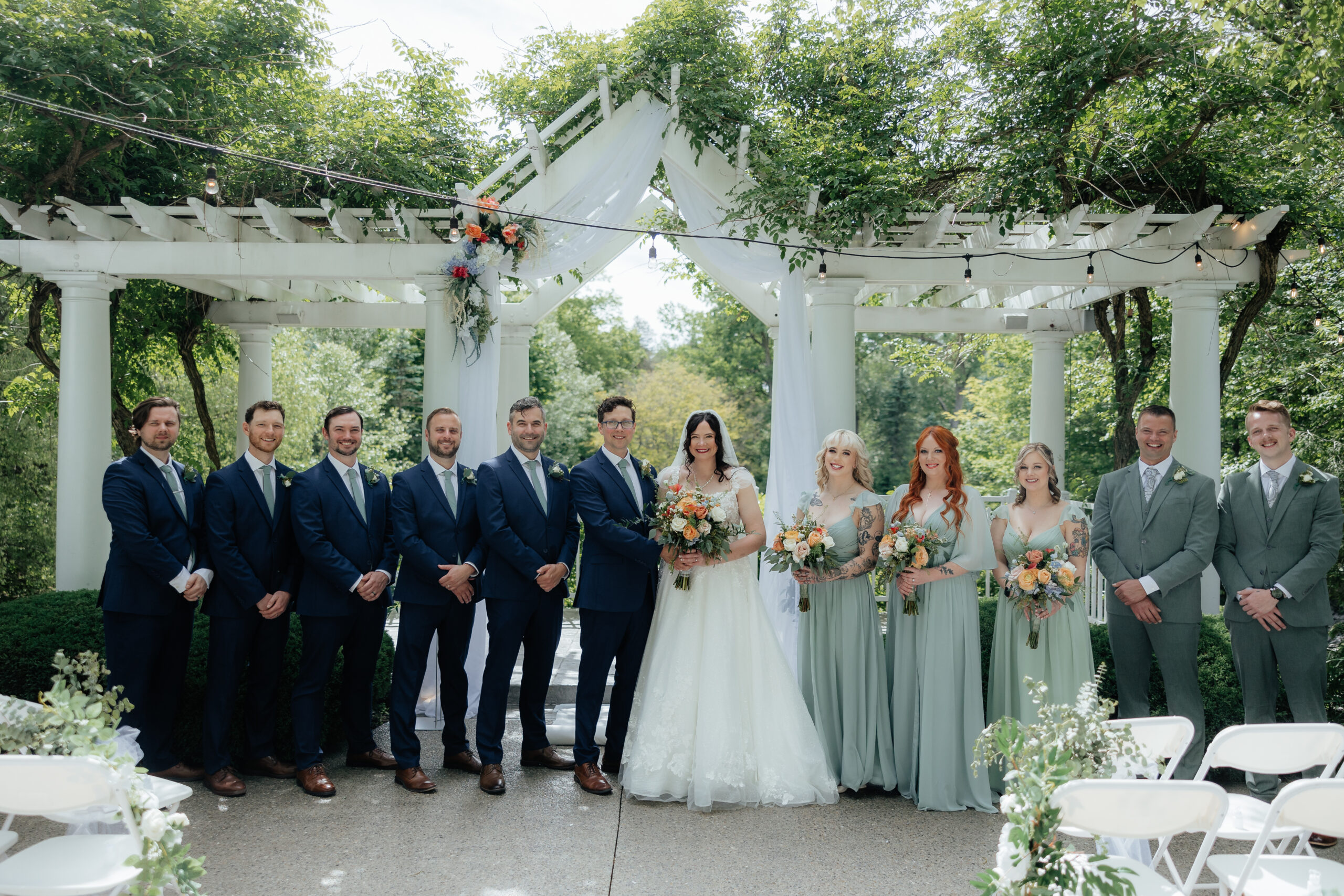A wedding party poses at the head of the outdoor ceremony space for the Grand Ballroom at Kloc's Grove in West Seneca, New York.