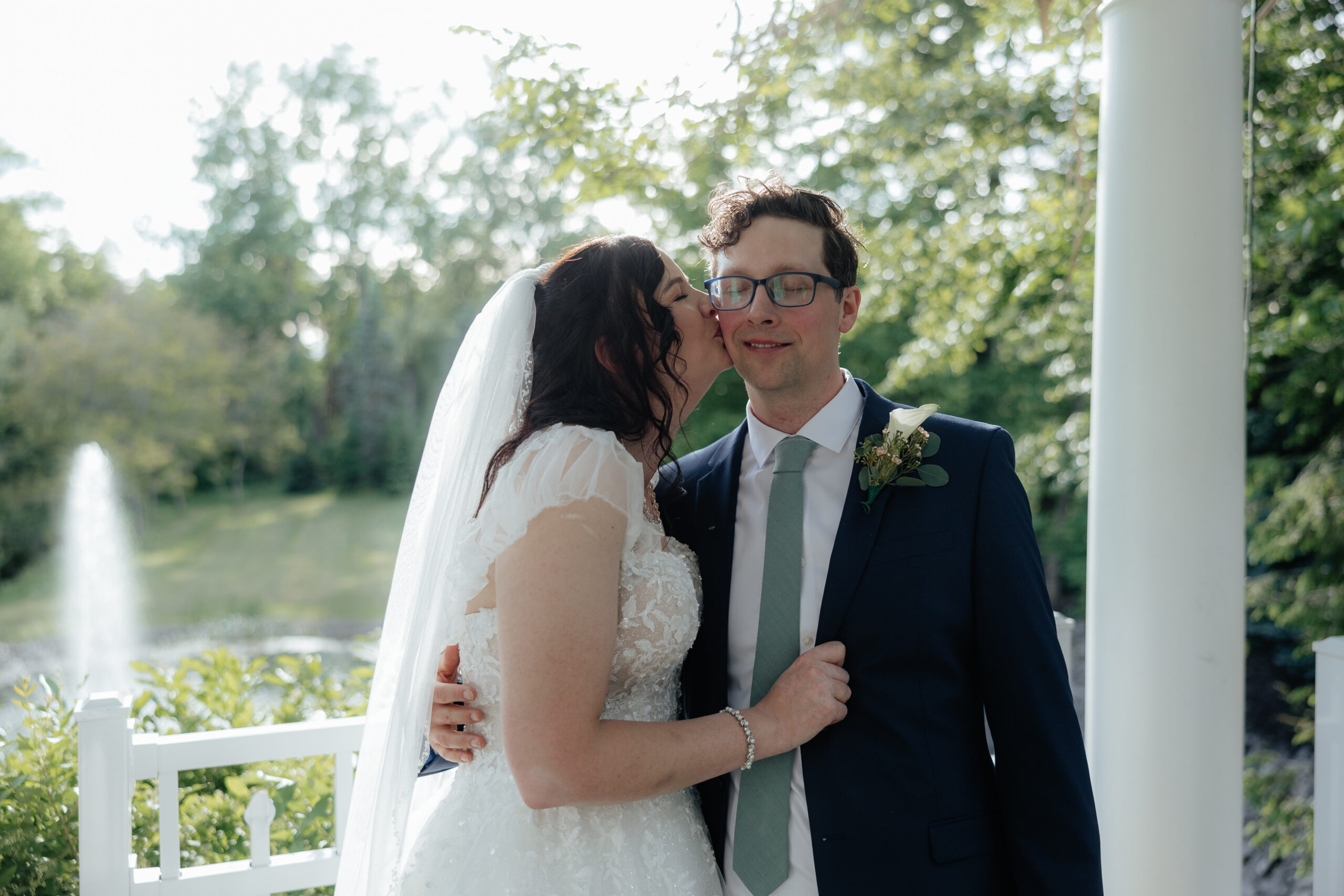 A bride and groom pose in front of the pond at golden hour at Kloc's Grove wedding venue in Buffalo, New York.