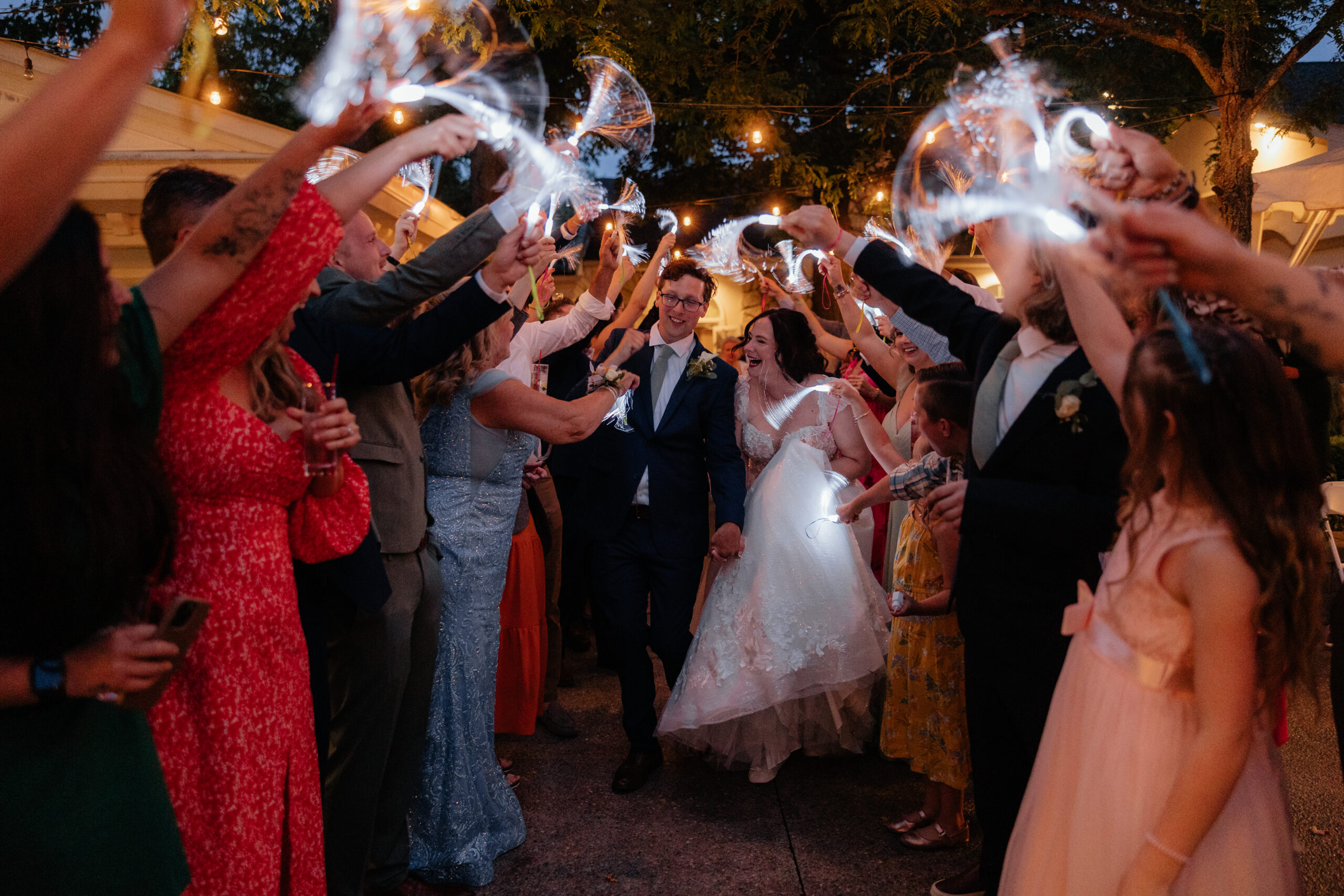 A bride and groom run through their wedding guests for their grand exit at Kloc's Grove wedding venue in Buffalo, New York.